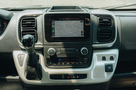 Inside an RV rental: a modern dashboard featuring a navigation screen, gear shifter, climate controls, and USB ports.
