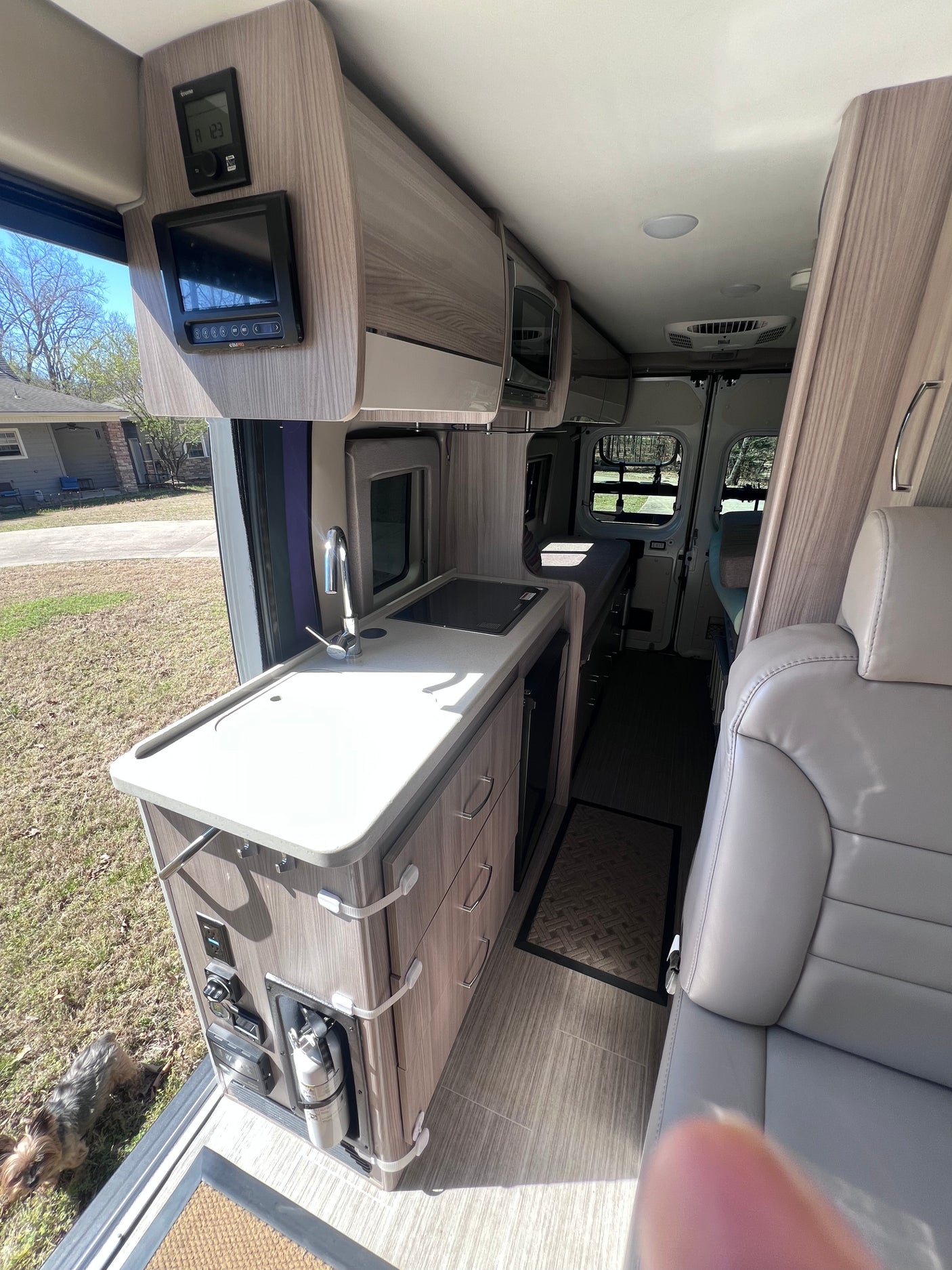 Modern camper van rental interior with full kitchen, tech controls, and comfortable living area. Pet-friendly adventures await!