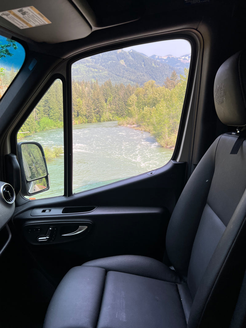 Scenic RV rental view: river, forests, and distant snow-capped mountains from the driver's seat perspective. — photo 12