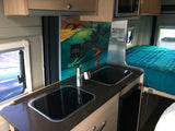 An RV rental's clever interior: compact kitchenette with two sinks/cooktops, vibrant mural, and a comfy bed for travelers.