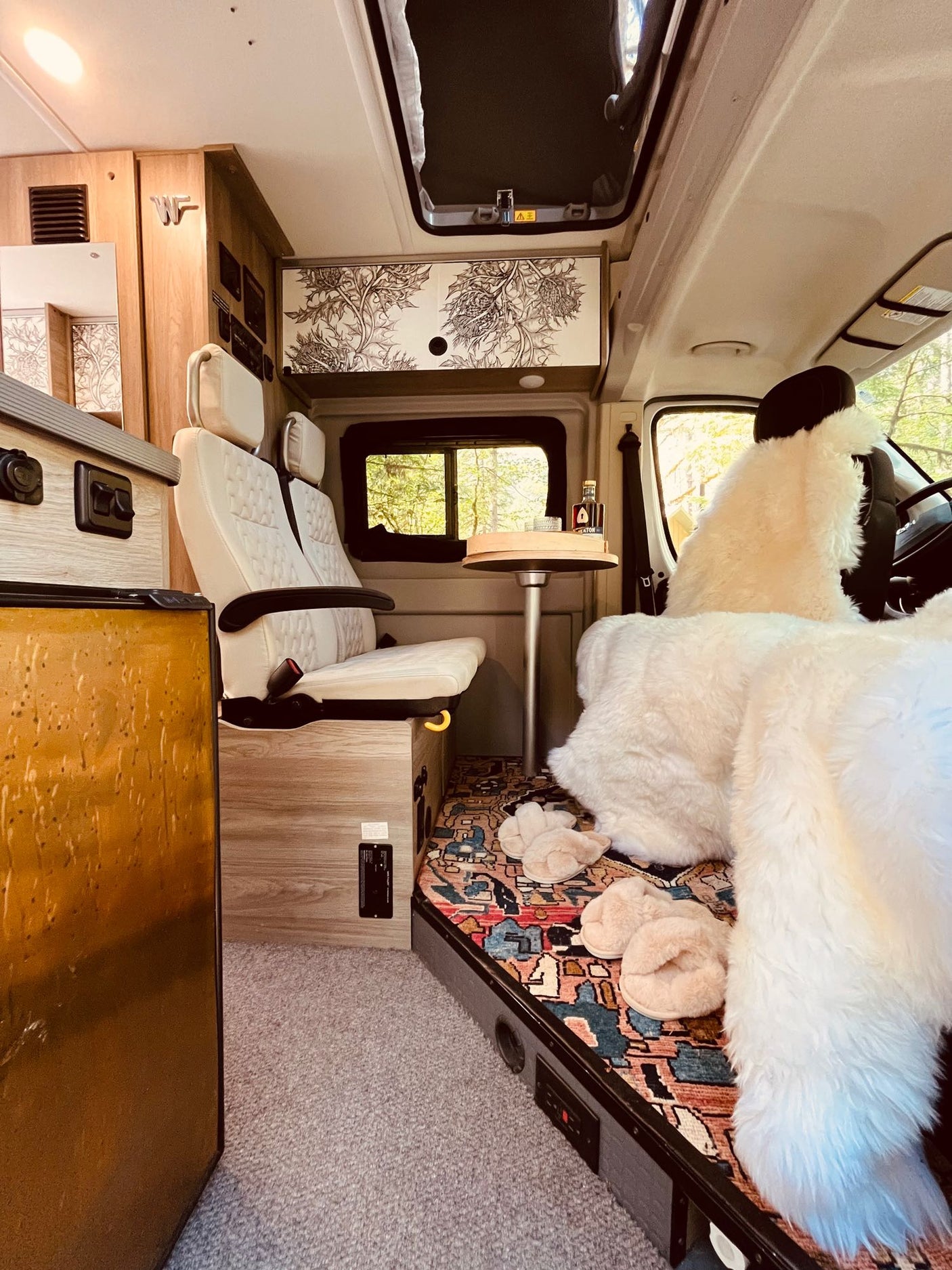 Inside a plush RV rental: swivel seats, patterned cabinets, and fluffy throws for a cozy, stylish camper interior.