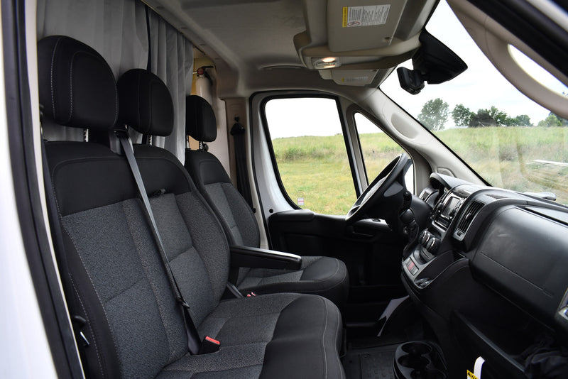 Inside an RV rental van: front seats, dashboard, and cabin, with curtains & fire extinguisher, overlooking a field. — photo 15