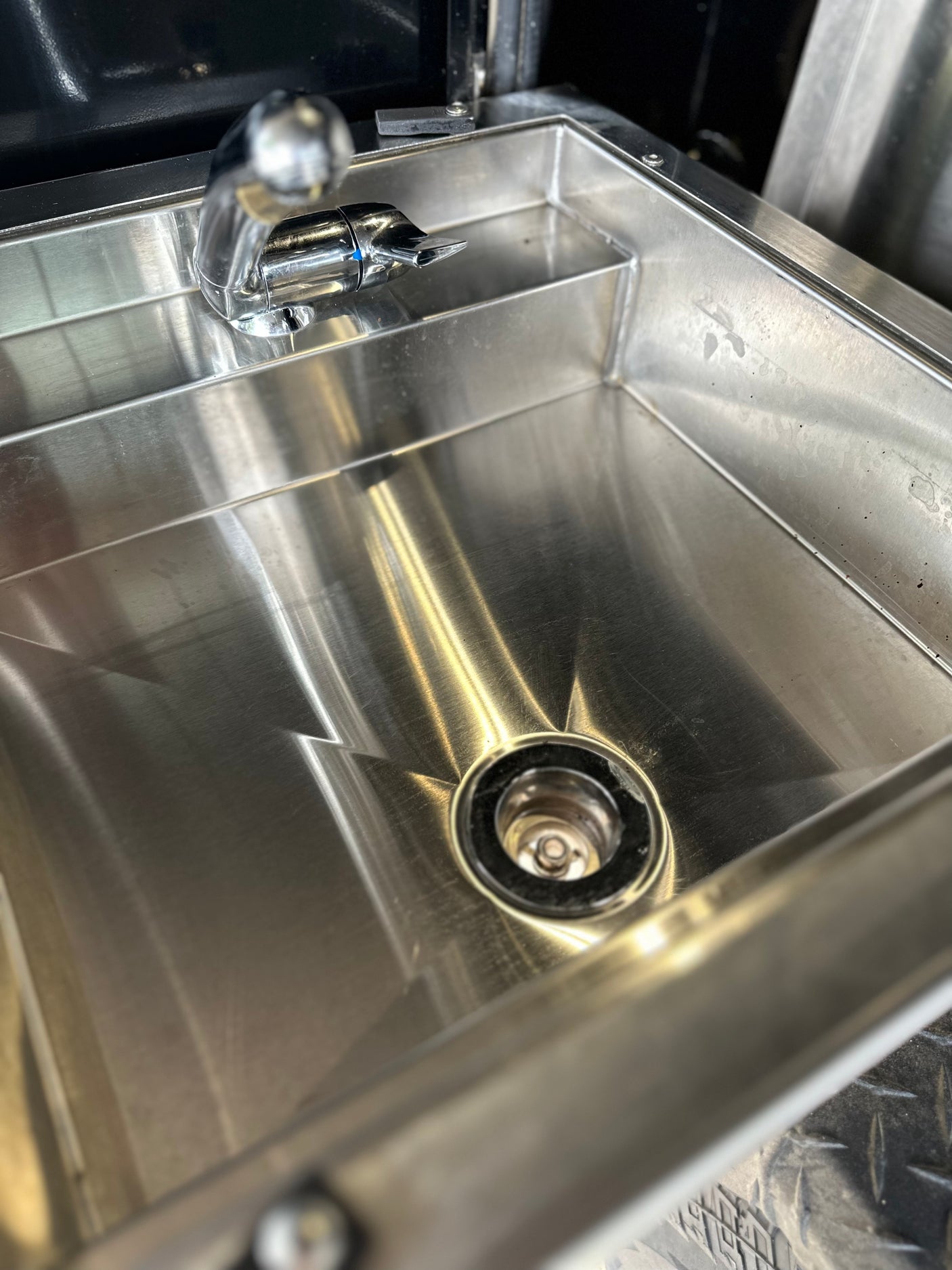 A stainless steel sink and faucet inside an RV rental, offering convenience for your travels.