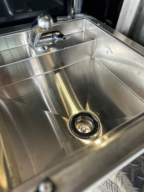A stainless steel sink and faucet inside an RV rental, offering convenience for your travels.