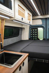 Spacious rv rental camper van interior featuring a comfy bed, kitchen sink, and clever overhead storage.