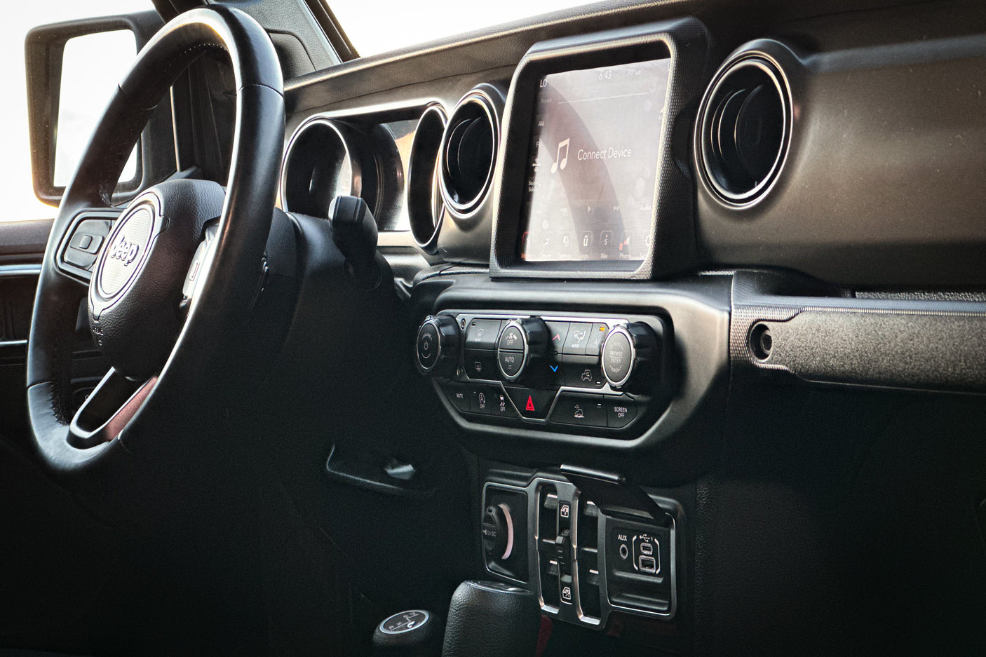 Modern Jeep dashboard: steering wheel, infotainment screen (showing 'Connect Device'), and climate controls. Ideal for RV rental trips.