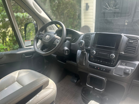 Inside an RV rental: modern driver's cockpit with Ram steering wheel, digital screen, and climate controls. Ready for your trip!