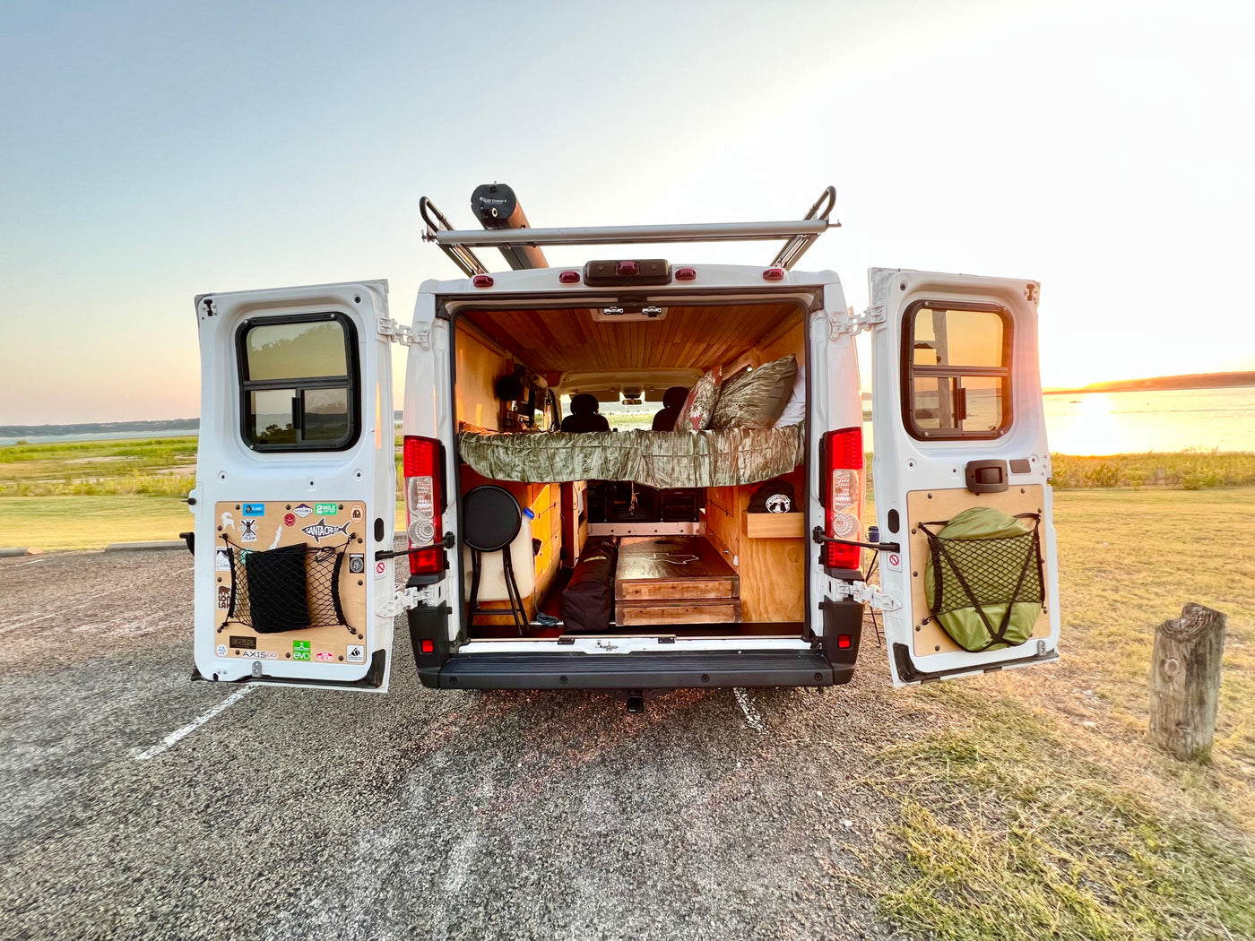 RV rental for adventure! Open doors show a custom camper interior, rooftop Road Shower, and sunset over the lake. — photo 8