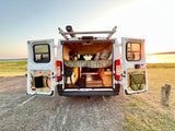 RV rental for adventure! Open doors show a custom camper interior, rooftop Road Shower, and sunset over the lake.