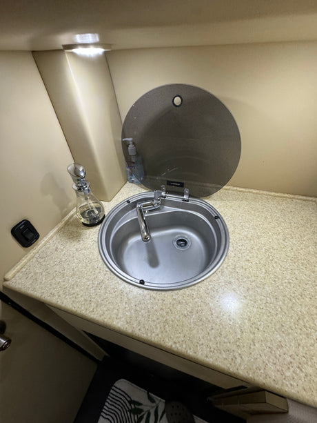 RV rental's compact bathroom sink with a chrome faucet, light countertop, and a Dometic lid.