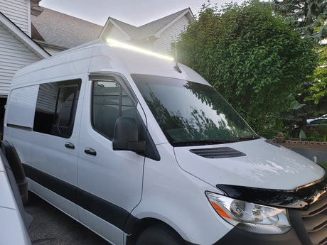 Bright white RV rental camper van, featuring a long roof light bar & tinted windows, ideal for overland trips.