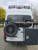 Explore with this white Sprinter RV rental van, featuring a roof rack, rear spare tire, storage box, and bike rack.