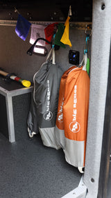 Inside an **rv rental**, Big Agnes bags hang near prayer flags and a light, showcasing organized storage for travel gear.