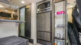 Experience this RV rental's clever interior: compact kitchen with microwave, fridge, pantry, and coat rack near the door.