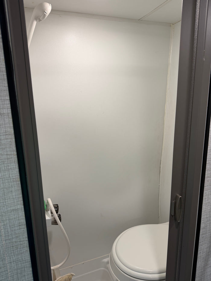 Compact RV rental bathroom with shower and toilet, offering essential amenities in a small space for convenience.