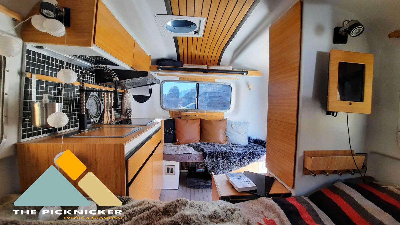 Modern RV rental interior: fully equipped kitchen, cozy living area with bed, and scenic window views. — photo 13