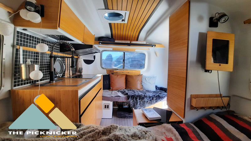 Modern RV rental interior: fully equipped kitchen, cozy living area with bed, and scenic window views. — photo 13