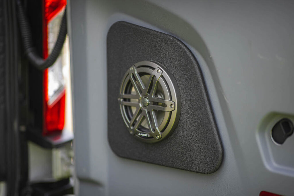 Built-in JL Audio speaker with metal grille on a custom panel in an RV rental. Enhancing the travel experience.