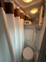 Compact RV rental wet bath featuring a toilet, shower, and curtain for convenient travel.