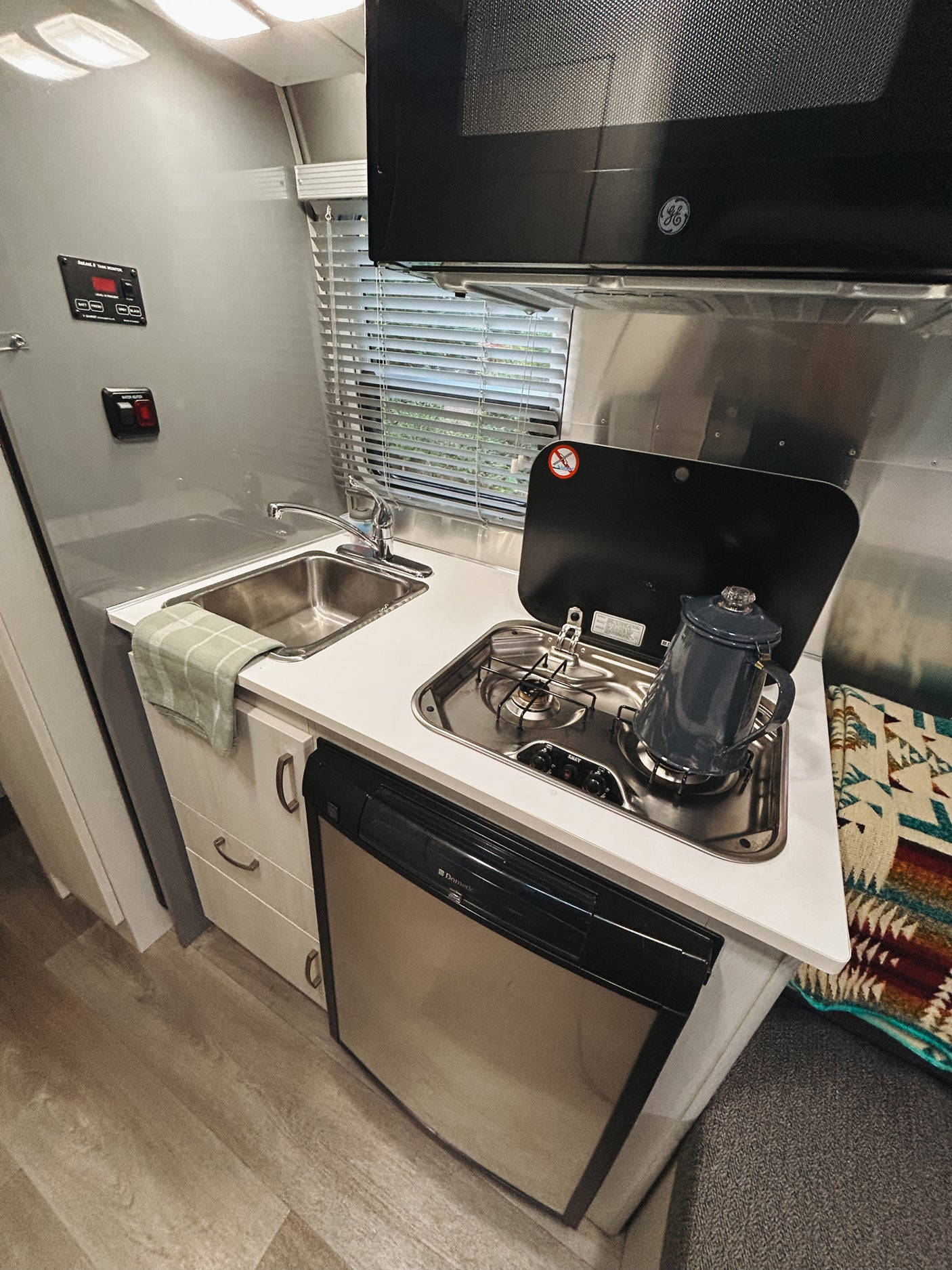 RV rental galley kitchen with a sink, two-burner stove, coffee pot, microwave, and refrigerator. Practical and compact.