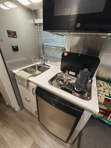 RV rental galley kitchen with a sink, two-burner stove, coffee pot, microwave, and refrigerator. Practical and compact.