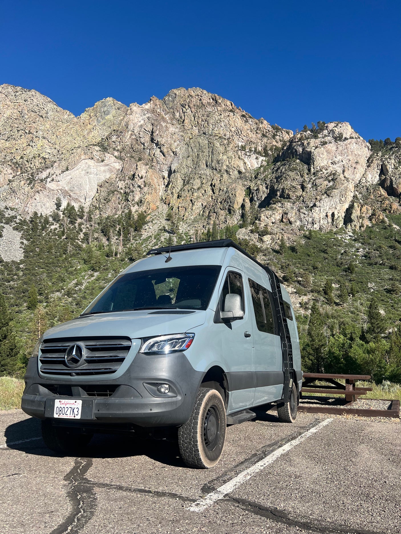 Adventure awaits with this Mercedes-Benz Sprinter RV rental parked at a rugged mountain campsite under a clear sky.