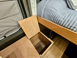 This RV rental features clever storage: an open wooden compartment next to a cozy quilted bed. Perfect for maximizing space on the go.