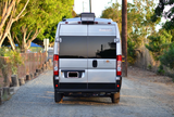 Silver Winnebago Sol rv rental van, rear view on a gravel path. It's ready for your next adventure.