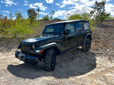 Black Jeep Wrangler parked on a rocky trail under a sunny sky, ideal for exploring, enhancing any travel or RV rental adventure.
