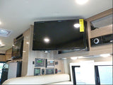 RV rental interior: cozy living space with mounted TV, microwave, system control panels, and entertainment unit.