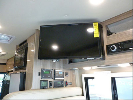 RV rental interior: cozy living space with mounted TV, microwave, system control panels, and entertainment unit.