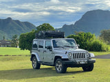 Adventure awaits! Silver Jeep with rooftop tent for your RV rental journey, set against stunning Kauai mountains.