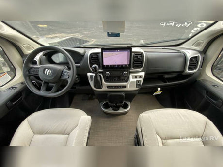 Inside an RV rental: a detailed view of the modern cockpit, featuring the steering wheel, large touchscreen display, and front seats.