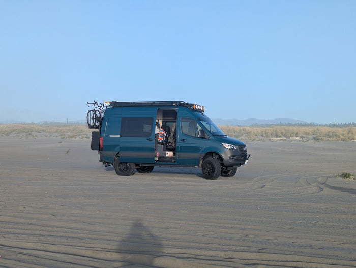 This teal adventure van, an ideal RV rental, is perfectly set up for beach camping with its bike and roof lights.
