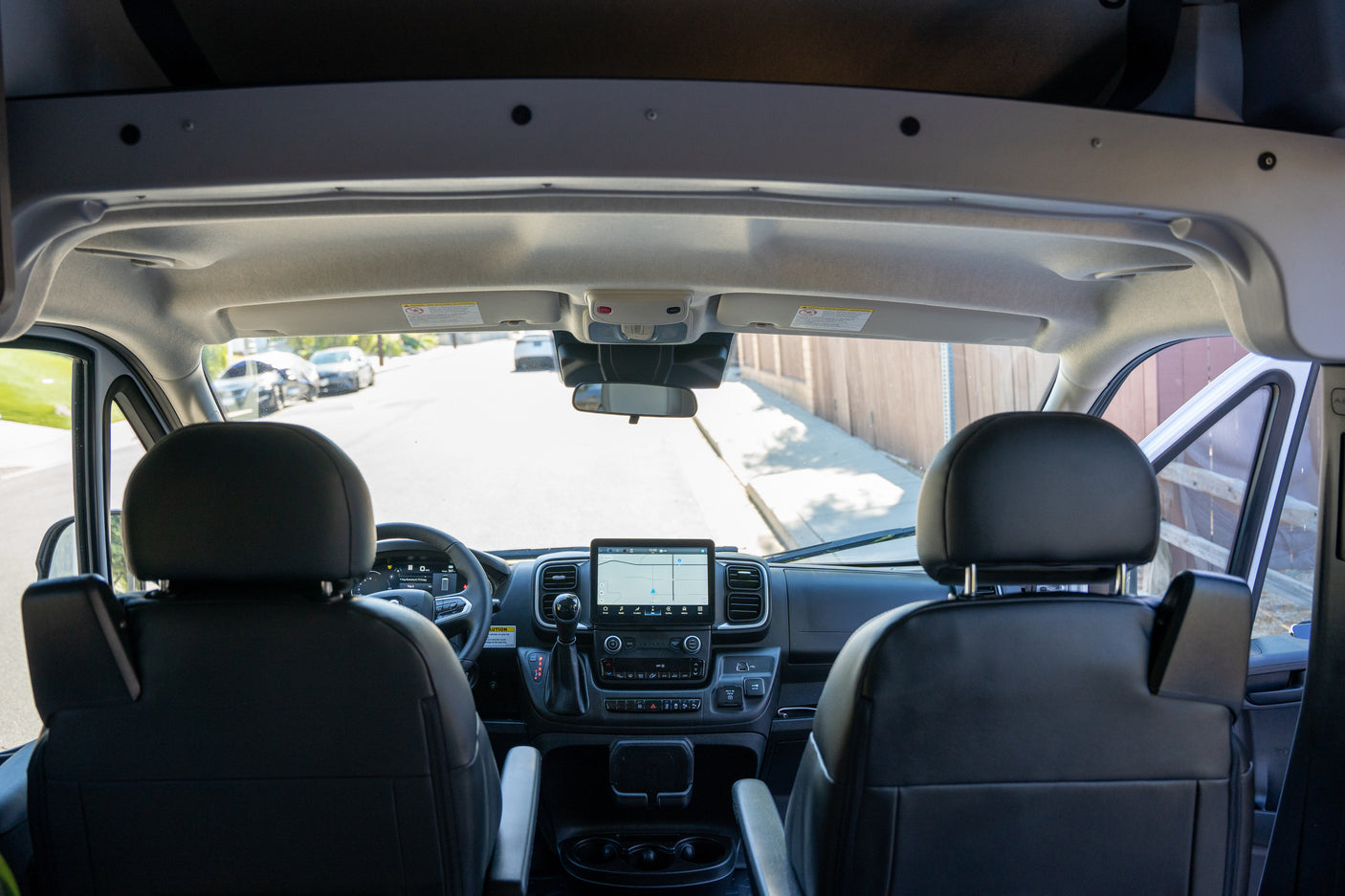 Front cabin view of an RV rental, showcasing the modern dashboard, navigation screen, and driver's area for a clear road ahead.