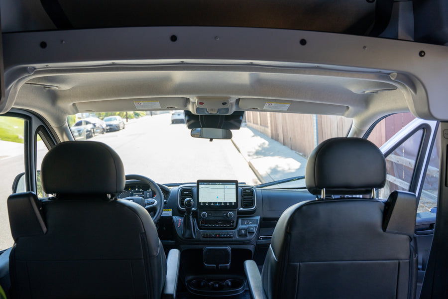 Front cabin view of an RV rental, showcasing the modern dashboard, navigation screen, and driver's area for a clear road ahead.