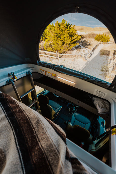 Cozy RV rental interior with pop-top roof open to beach views. Perfect for road trip adventures!