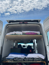 An RV rental setup: a white Ram truck tows a Mallard travel trailer on a scenic dirt camp path.