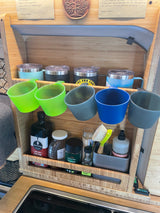 RV rental kitchen: efficient bamboo storage for travel mugs, cups, oil, and cleaning items.