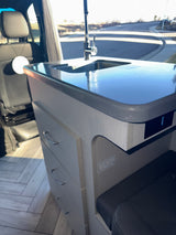 Explore this RV rental's cozy interior, showcasing a modern kitchen with sink, counter, drawers, and seating.