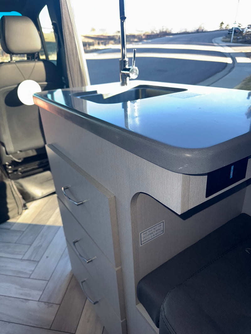  and two front seats.|Experience comfort in this rv rental: a well-lit interior featuring a dining area with gray upholstered benches — photo 9