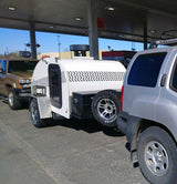 White teardrop trailer towed by a silver SUV at a gas station. Ideal for an rv rental adventure or camping trip.