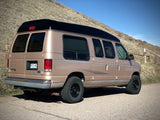 Tan Ford Econoline high-top camper van, an ideal RV rental for exploring scenic Colorado trails.
