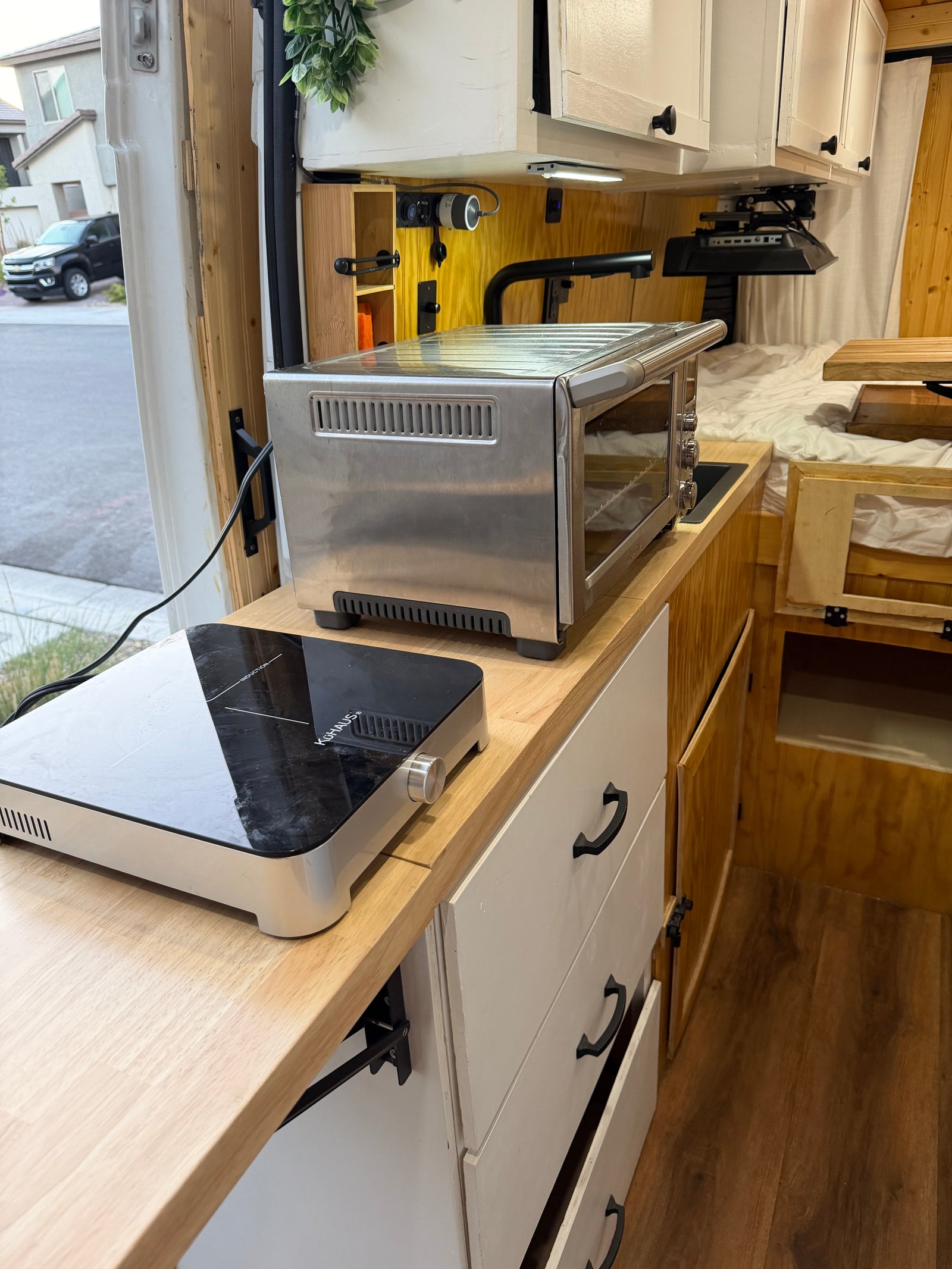 Functional RV rental kitchen with induction cooktop & toaster oven on a light wood counter for compact living.