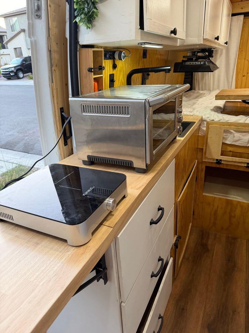 Functional RV rental kitchen with induction cooktop & toaster oven on a light wood counter for compact living. — photo 9