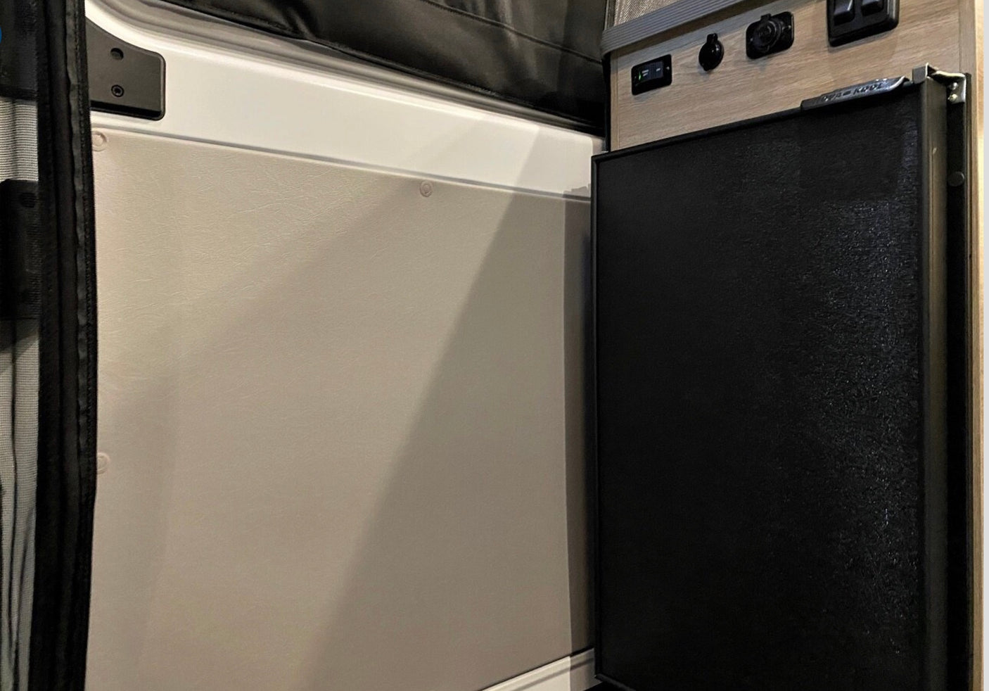 RV rental with compact fridge, power panel (USB/12V), and wall panel with screen.