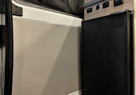 RV rental with compact fridge, power panel (USB/12V), and wall panel with screen.
