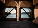 Peaceful rv rental view from bed: tranquil water, mountains, and twilight sky through screened back doors.