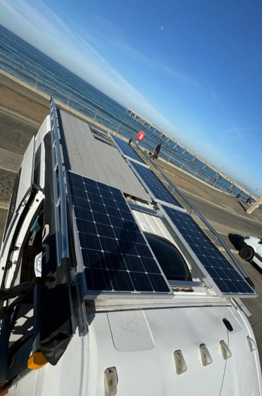 RV rental: Solar-powered van by the ocean with a pier in the distance. Perfect for off-grid beach adventures!
