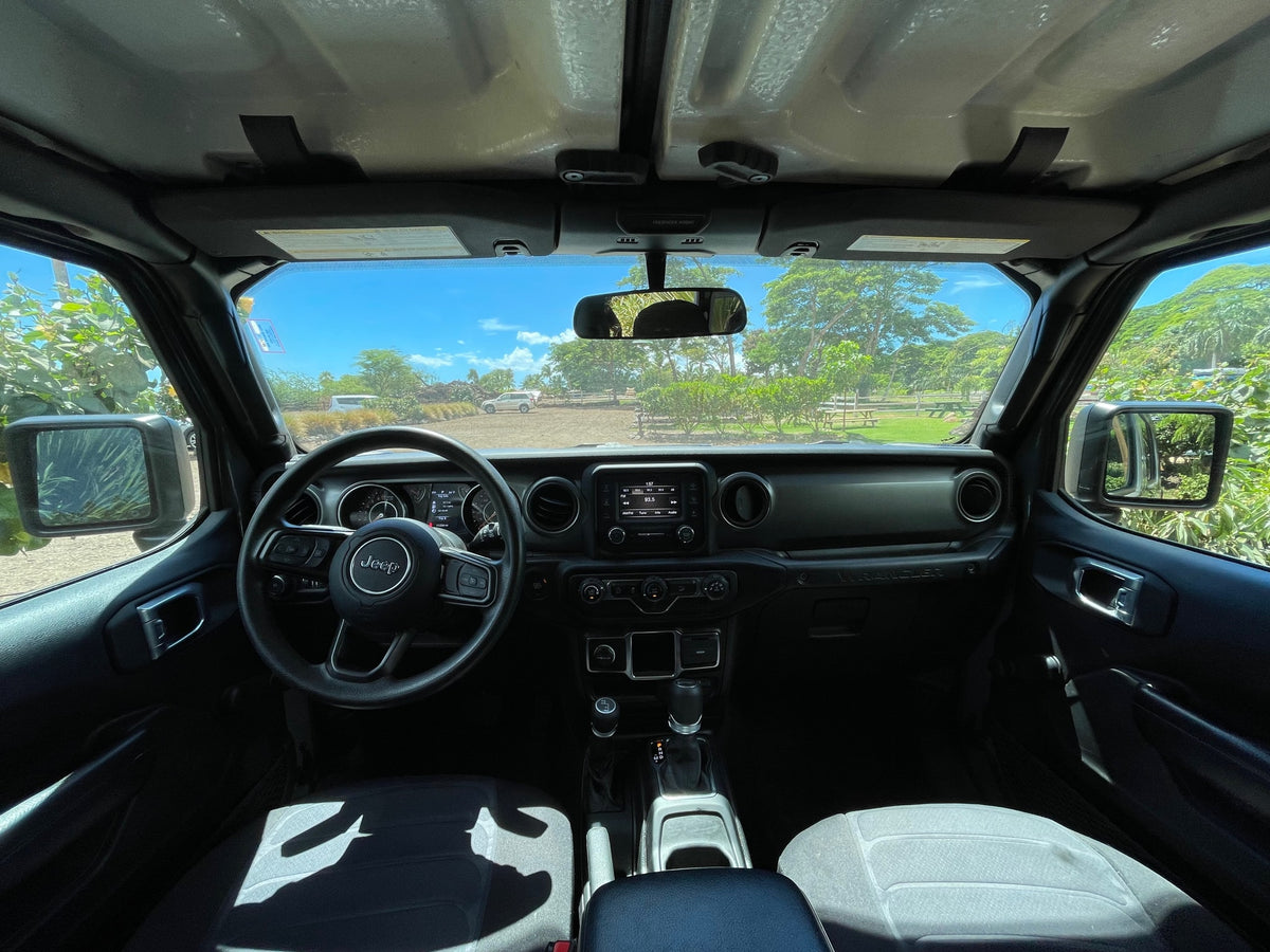 The interior of a Jeep Wrangler, perfect for an RV rental road trip. Dash, steering wheel, and sunny outdoor scenery visible. — photo 5